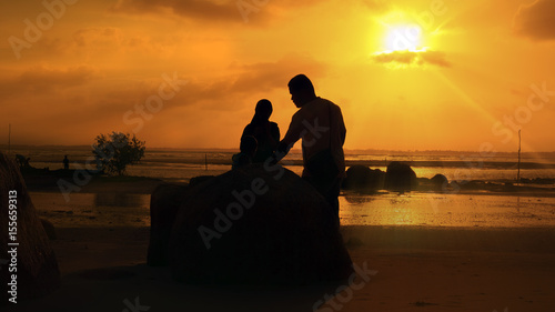 silhouette people, a husband and wife with their children on the beach.