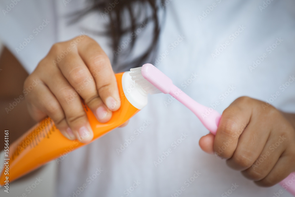 Naklejka premium Little girl squeezes the toothpaste on the toothbrush prepare for brush her teeth