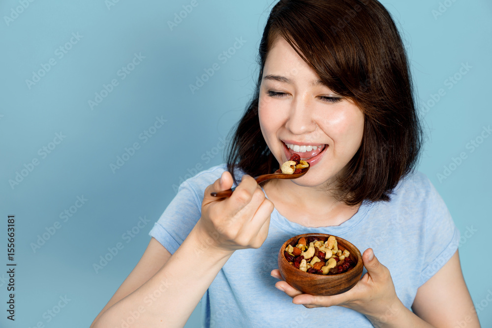 young woman eating granola on blue background. Macrobiotics concept. low carb diet. organic foods. young woman eating granola on blue background. Macrobiotics concept. low carb diet. organic foods.