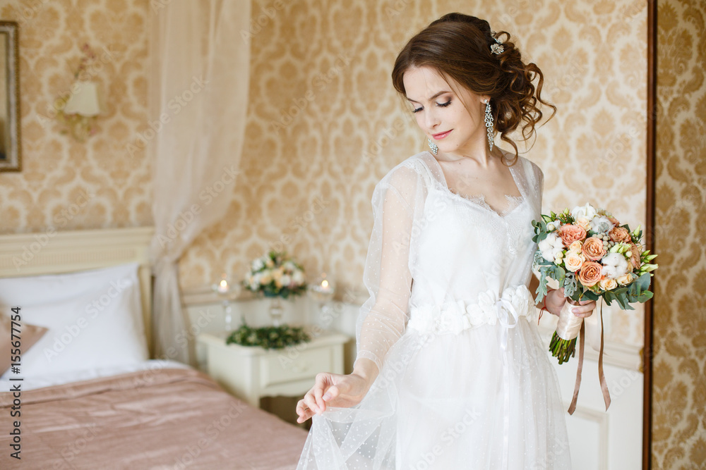 Pretty young Bride. Boudoir morning of the bride. Looking on her bouquet Pretty young Bride. Boudoir morning of the bride. Looking on her bouquet