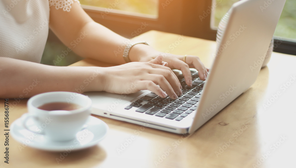 Fototapeta premium Concentrated at work. Confident young woman in smart casual wear working on laptop while sitting near window in creative office or cafe