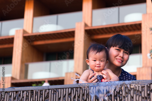 Asian young mother and cute nine month baby enjoy swimming pool.