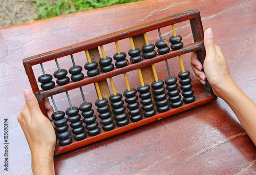 Woman hands holding Chinese ABACUS old antique calculator retro finance education ,tool work business accounting photo