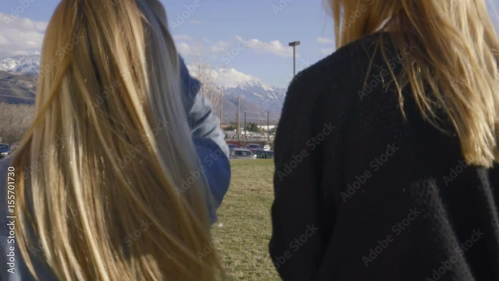 Friends Walk Toward Campus Parking Lot, One Girl Uses Smartphone Friends Walk Toward Campus Parking Lot, One Girl Uses Smartphone