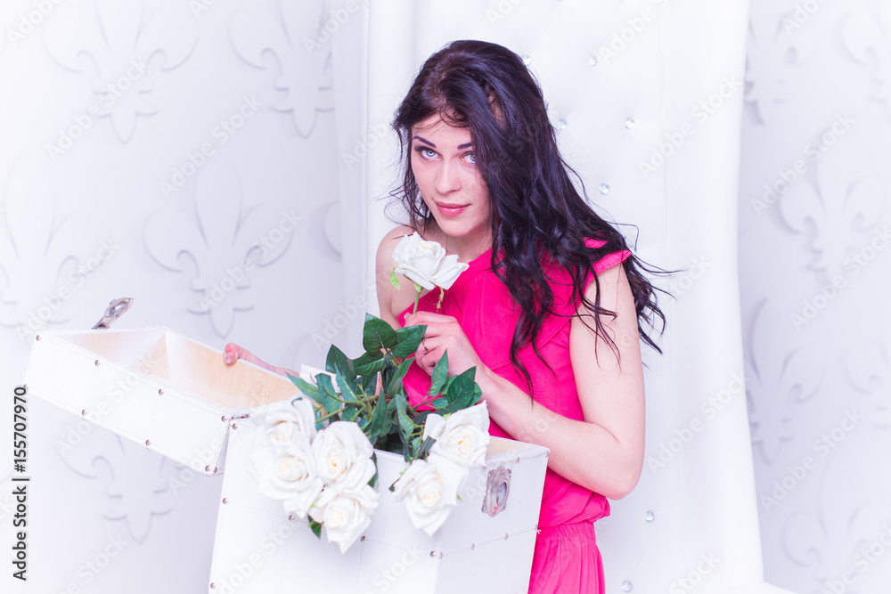 Sexy and attractive brunette woman with long hair and green eyes in white vintage white interior with box gift
