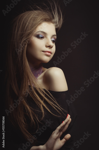 Lovely young woman with glitter pigment on her neck and wind blowing her hair