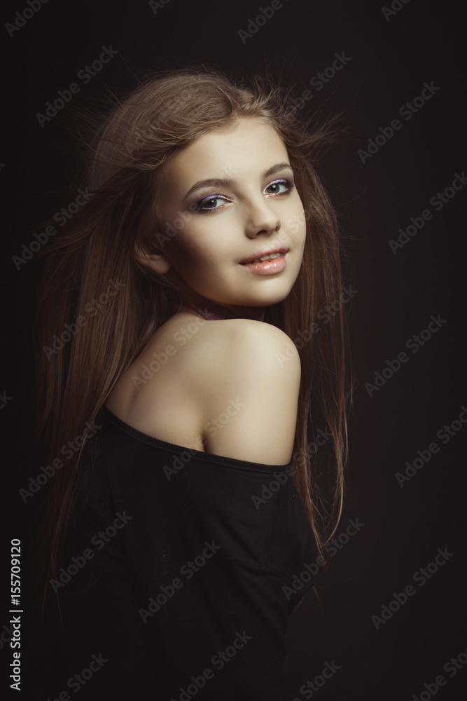 Naklejka premium Smiling young model in black dress posing at studio