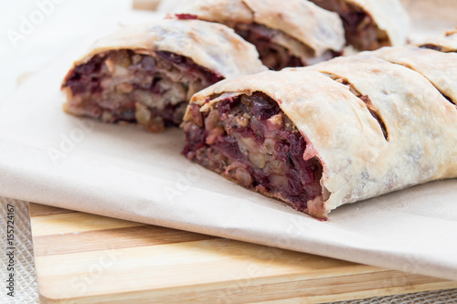 Apple strudel with cherries and raisins on cutting board