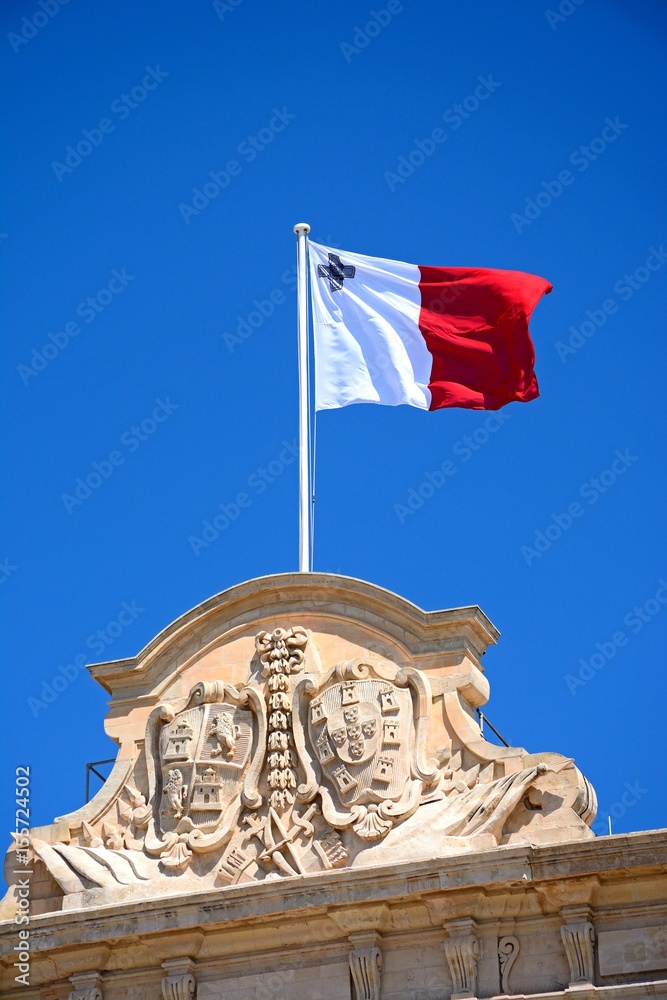 Maltese flag and coast of arms on top of the Auberge de Castille in Castille Square, Valletta, Malta.
