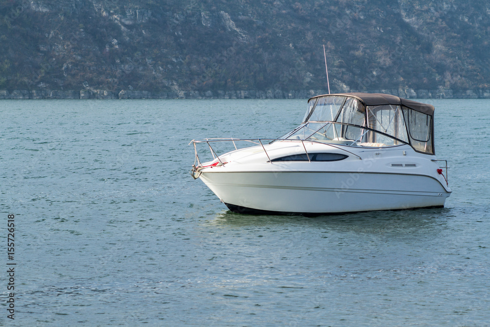 White boat in the water on the background of the hill.