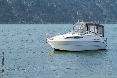 White boat in the water on the background of the hill.