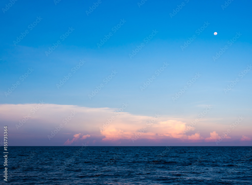 Clouds and moon in sunset sky over sea