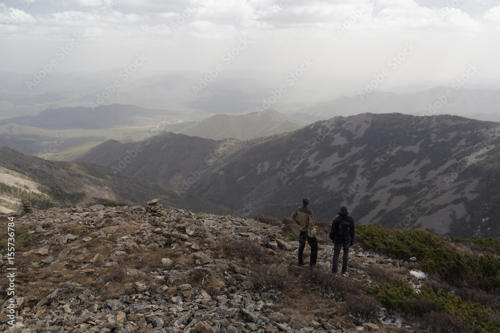Two people stand side by side on top of the mountain and admire the mountain scenery Two people stand side by side on top of the mountain and admire the mountain scenery