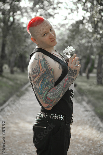 alternative tattoo rehead man walking on the apple tree park with flowers photo