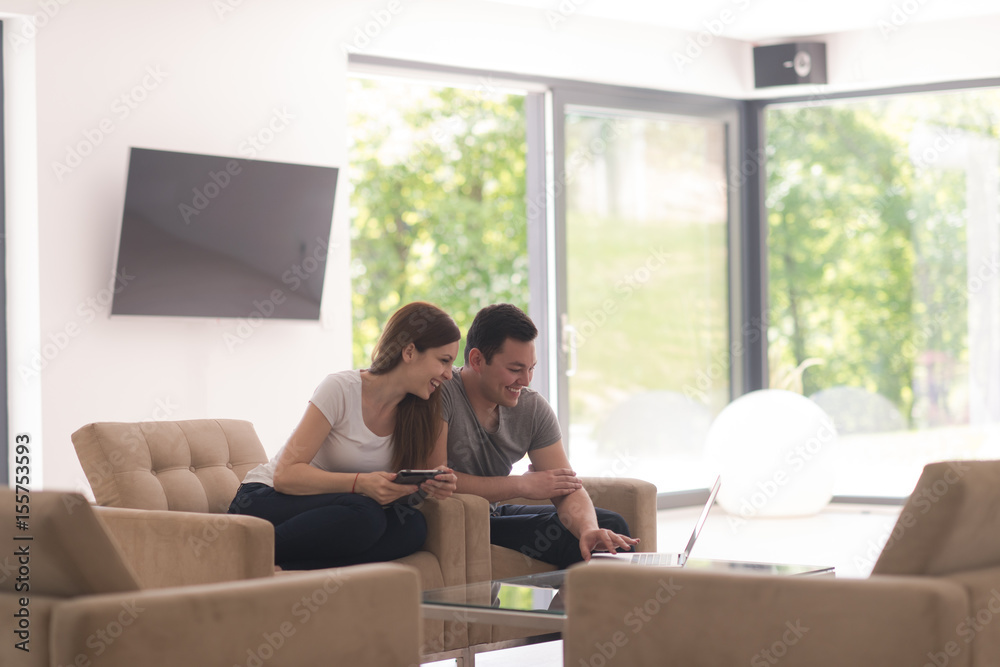 couple relaxing at home with tablet and laptop computers couple relaxing at home with tablet and laptop computers
