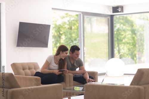 couple relaxing at home with tablet and laptop computers