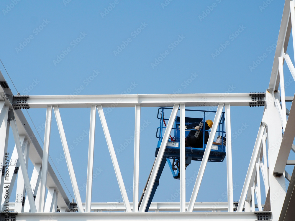 Naklejka premium construction worker at construction site using lifting boom machinery