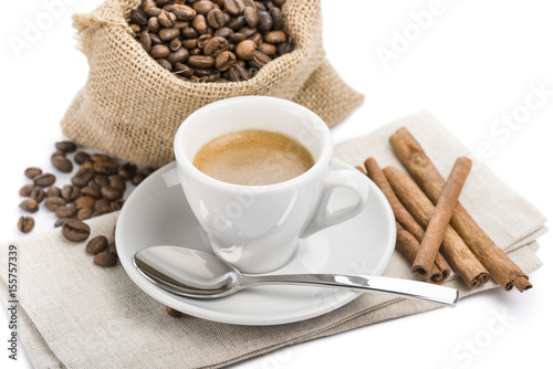 cup of coffee on napkin with canvas bag full of coffee beans and cinnamon  on white background