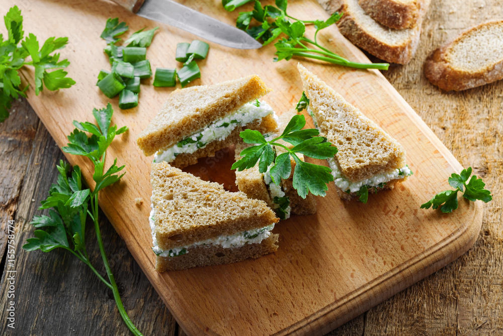 Sandwiches made of rye bread, cream cheese, green onion and fresh parsley on a rustic table. Delicious healthy appetizers. Top view. Sandwiches made of rye bread, cream cheese, green onion and fresh parsley on a rustic table. Delicious healthy appetizers. Top view.
