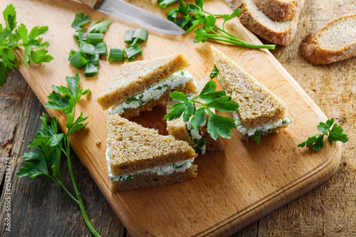 Sandwiches made of rye bread, cream cheese, green onion and fresh parsley on a rustic table. Delicious healthy appetizers. Top view.