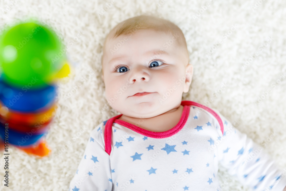 Cute baby girl playing with colorful wooden rattle toy Cute baby girl playing with colorful wooden rattle toy