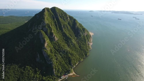 High rock in the ocean Sister hill Nakhodka Primorsky Krai Russia. Aerial drone forward flight 4k. Beautiful Russian nature blue water. Japan sea summer sunny day.  photo