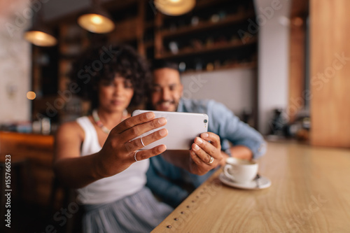 Couple taking selfie with smart phone at cafe