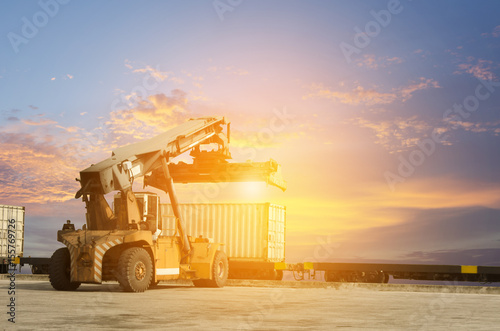 stacker and container train freight for import export concept in sunset background