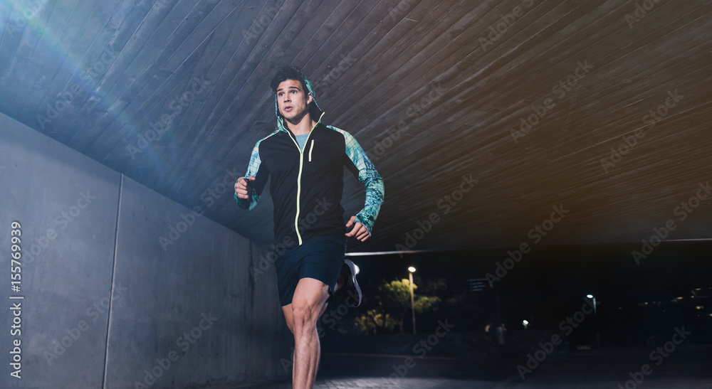 Fototapeta premium Young man jogging at night in city
