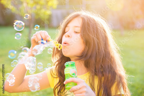 Girl blowing soap bubbles outdoors