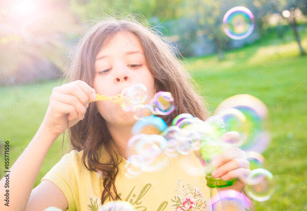 Girl blowing soap bubbles outdoors