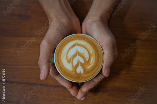 Male hands holding a cup of coffee on wooden table