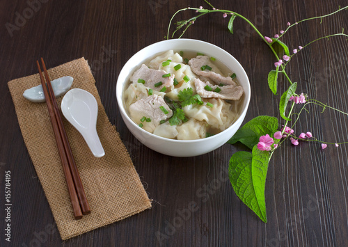 Shrimp wonton with braised pork in soup on wooden table / Select focus style, and flower make refreshingly of food