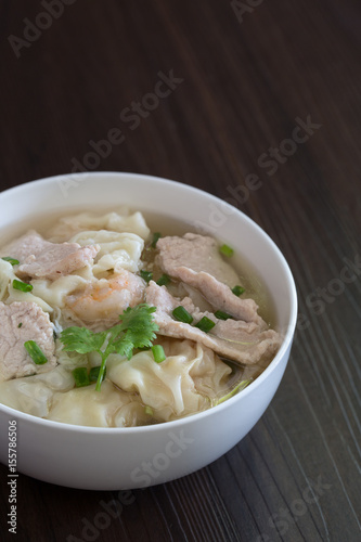 Shrimp wonton with braised pork in soup on wooden table / Select focus image and space for text.