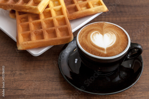 Obraz na płótnie Coffee cup of latte art heart shape beside with some waffle on wooden background w salonie