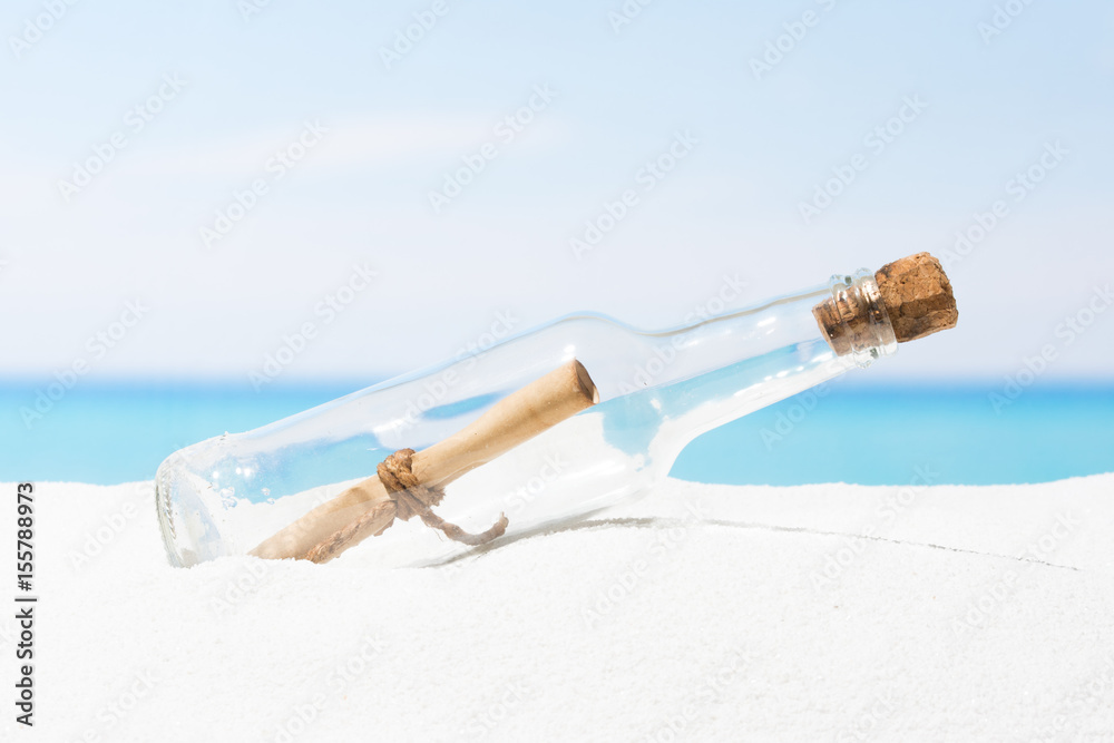 Message in bottle on beach with white sand,  in tropical sea