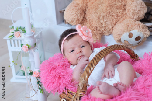 newborn baby girl in pink blanket lying in basket, cute card composition photo