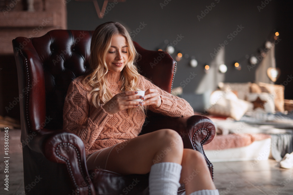 Woman with beverage in armchair