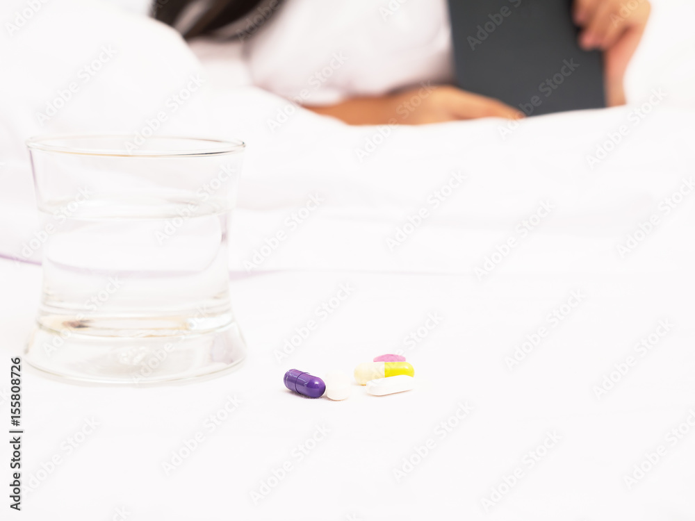 A pill on bed with a glass of water A pill on bed with a glass of water