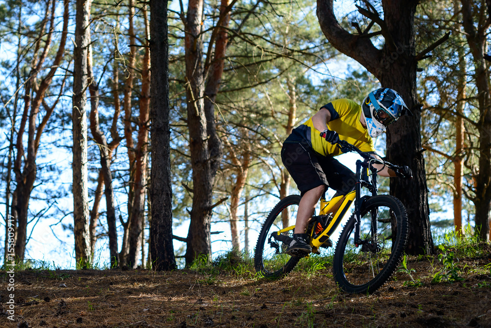 Naklejka premium Professional Cyclist in Yellow T-shirt and Helmet Riding the Bike in Forest. Extreme Sport Concept.