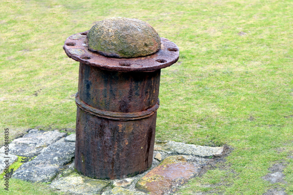 Old steel and concrete boat mooring bollard on stone base Old steel and concrete boat mooring bollard on stone base