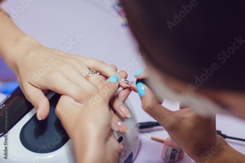 Manicure in the spa salon. Drawing of nail polish. Spa manicure  nail care. Girl does a manicure. The concept of hand care.