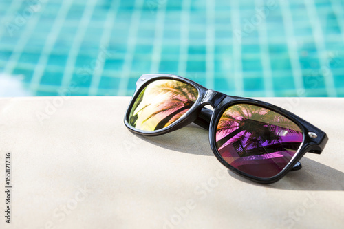 Summer concept, polaroid sunglasses on swimming pool edge, outdoor day light