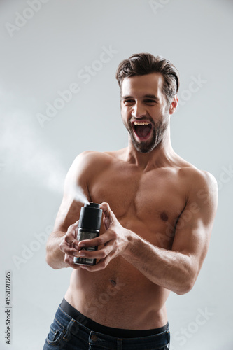 Joyful man playing with deodorant