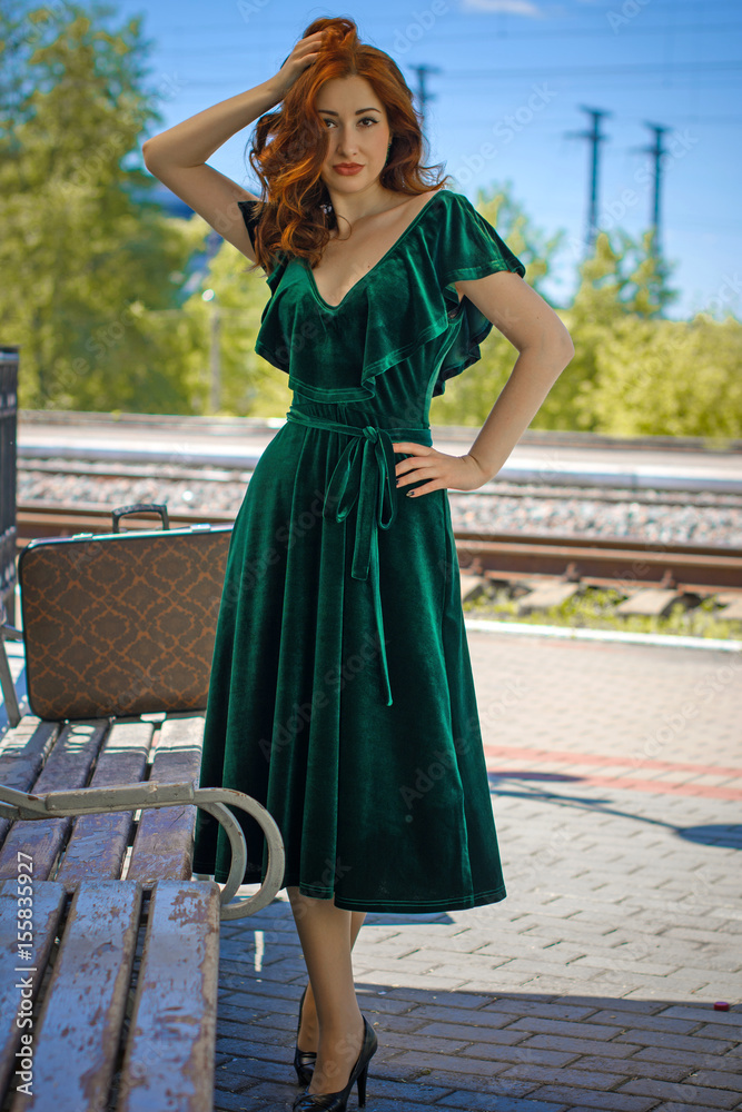 Gorgeous redhead woman in green velvet dress in vintage style with a  suitcase on the platform Stock Photo | Adobe Stock
