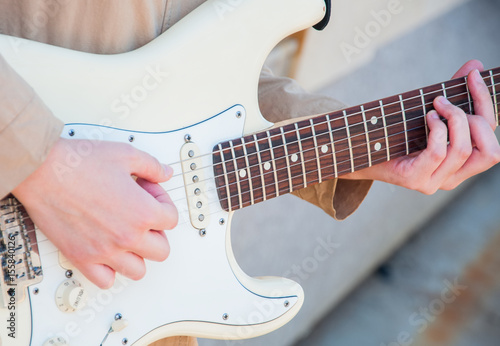 Close up of young girl's hands playing guitar out of doors