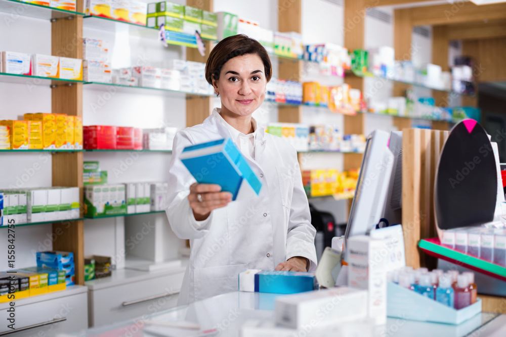 Female pharmacist offering help in choosing at counter in pharmacy