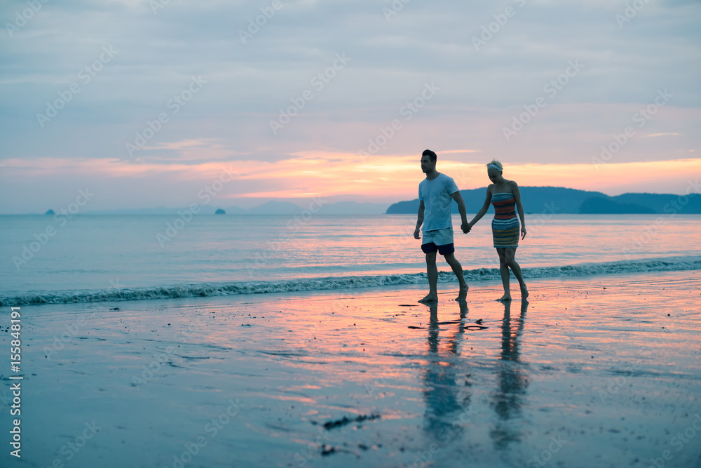 Couple Walking Holding Hands On Beach At Sunset, Young Tourist Man And Woman On Sea Holiday While Summer Vacation