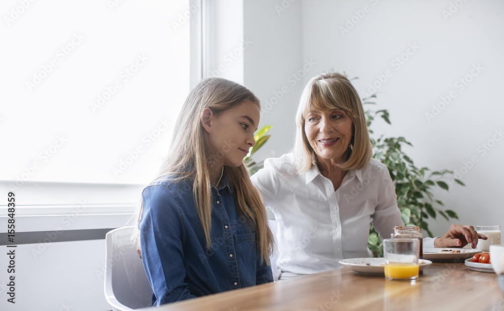 Grandmother and granddaughter sitting at dining table at breakfast time. Grandmother and granddaughter sitting at dining table at breakfast time.