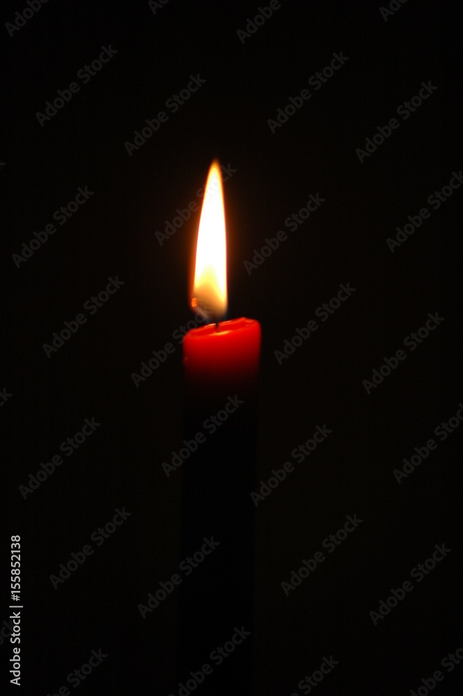 Vertical shot of red candle burning against a dark background Vertical shot of red candle burning against a dark background